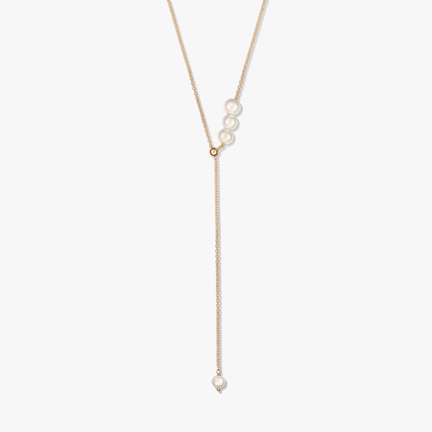 Delicata collana lariat in argento sterling placcato oro con un trio di perle coltivate al cursore scorrevole e una singola goccia di perla, su sfondo bianco.