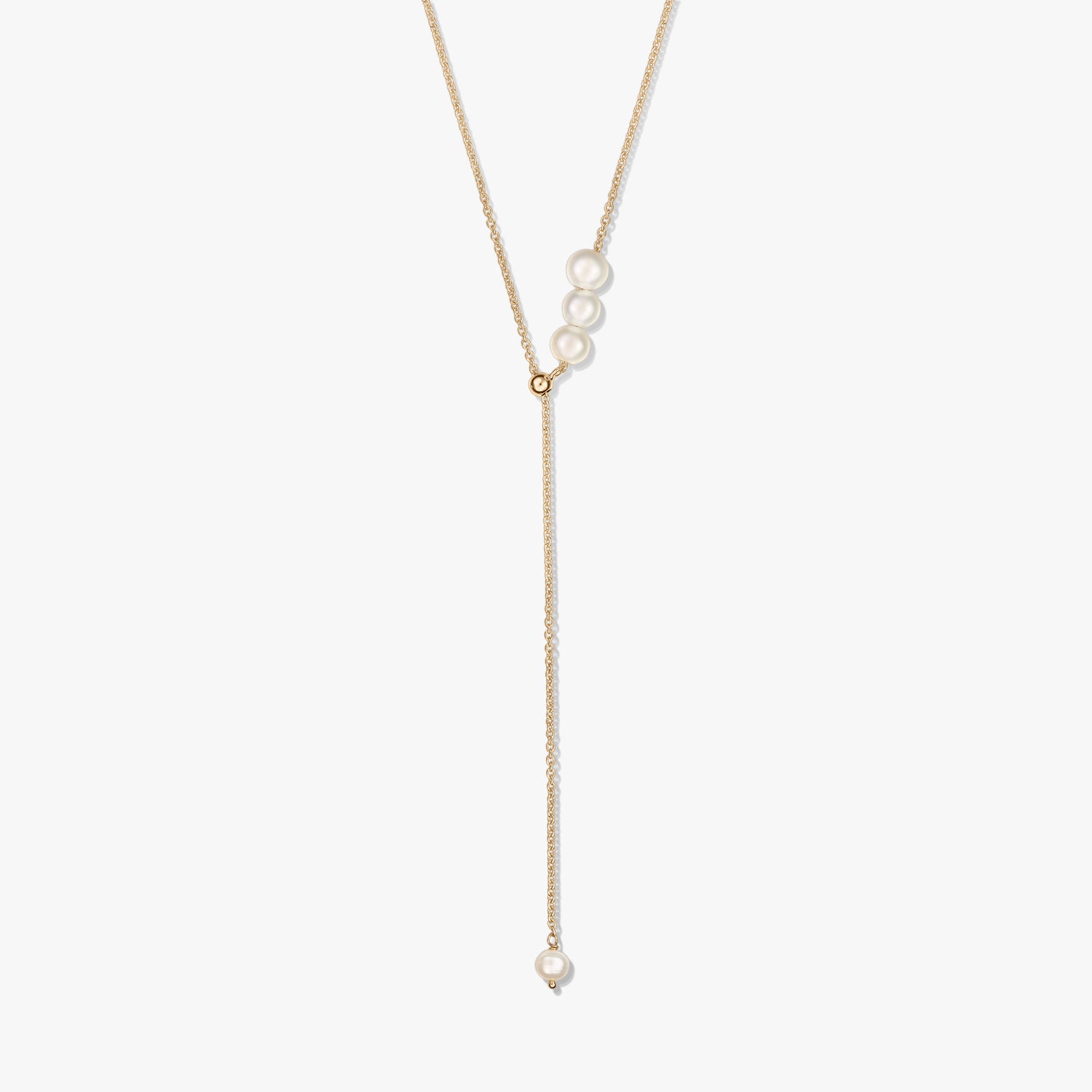 Delicata collana lariat in argento sterling placcato oro con un trio di perle coltivate al cursore scorrevole e una singola goccia di perla, su sfondo bianco.
