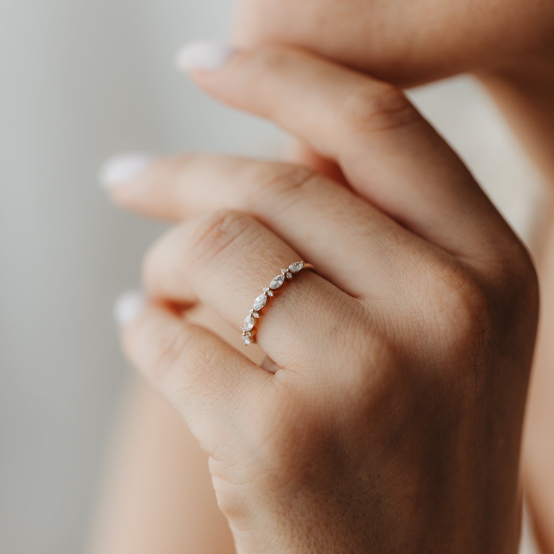 Primo piano di una mano che indossa l'anello Fiorelle in oro giallo con diamanti a taglio marquise e rotondo alternati.