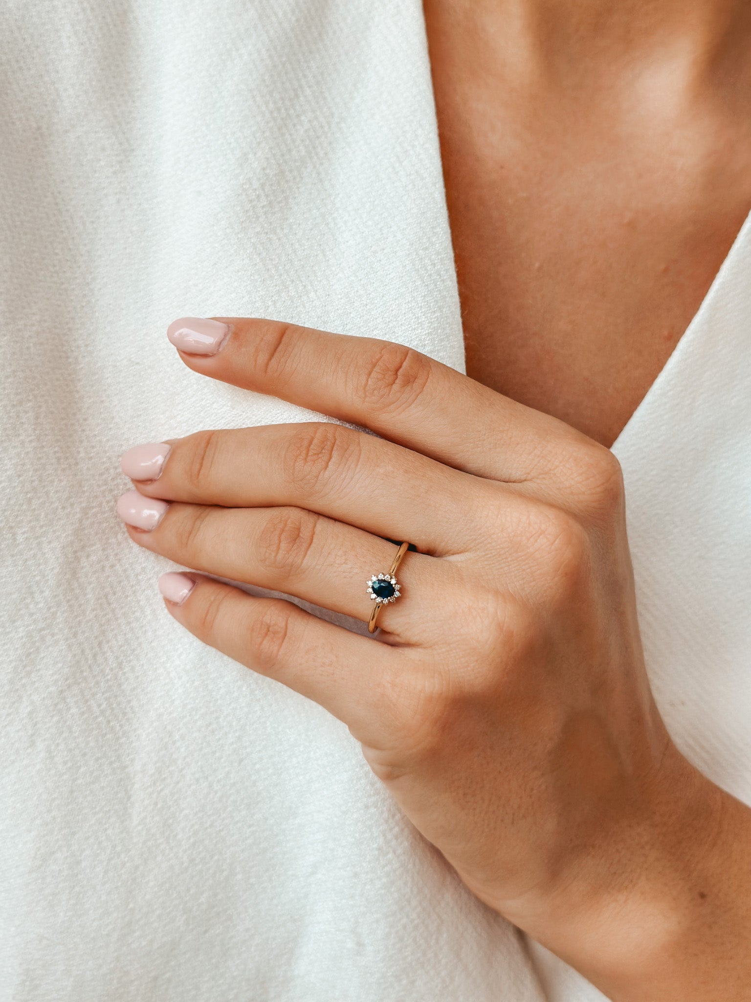 Primo piano di una mano che indossa un anello d'oro con zaffiro e diamanti