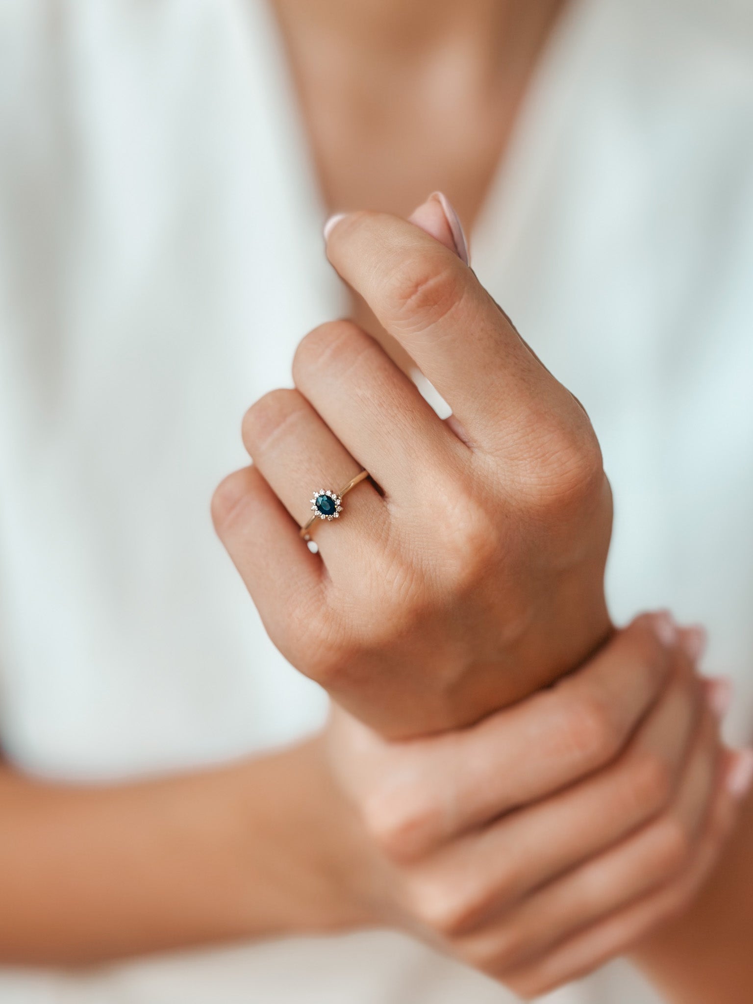 Primo piano di una mano che indossa un anello Genn d'oro con zaffiro e diamanti.