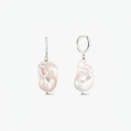 Paio di orecchini a cerchio in argento sterling con grandi perle barocche bianche irregolari su sfondo bianco pulito.