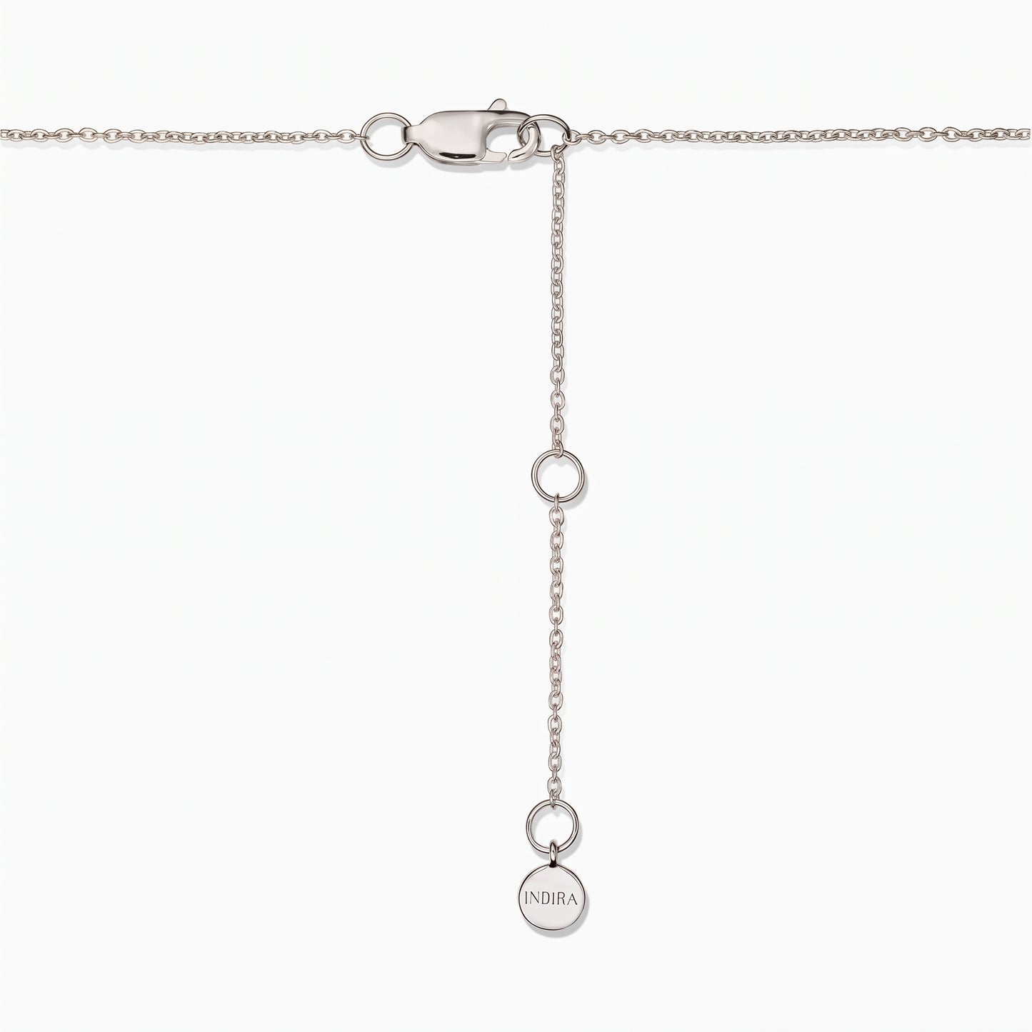 Primo piano della chiusura di una collana in argento sterling con catenella di prolunga regolabile e una piccola targhetta rotonda Indira su sfondo bianco.