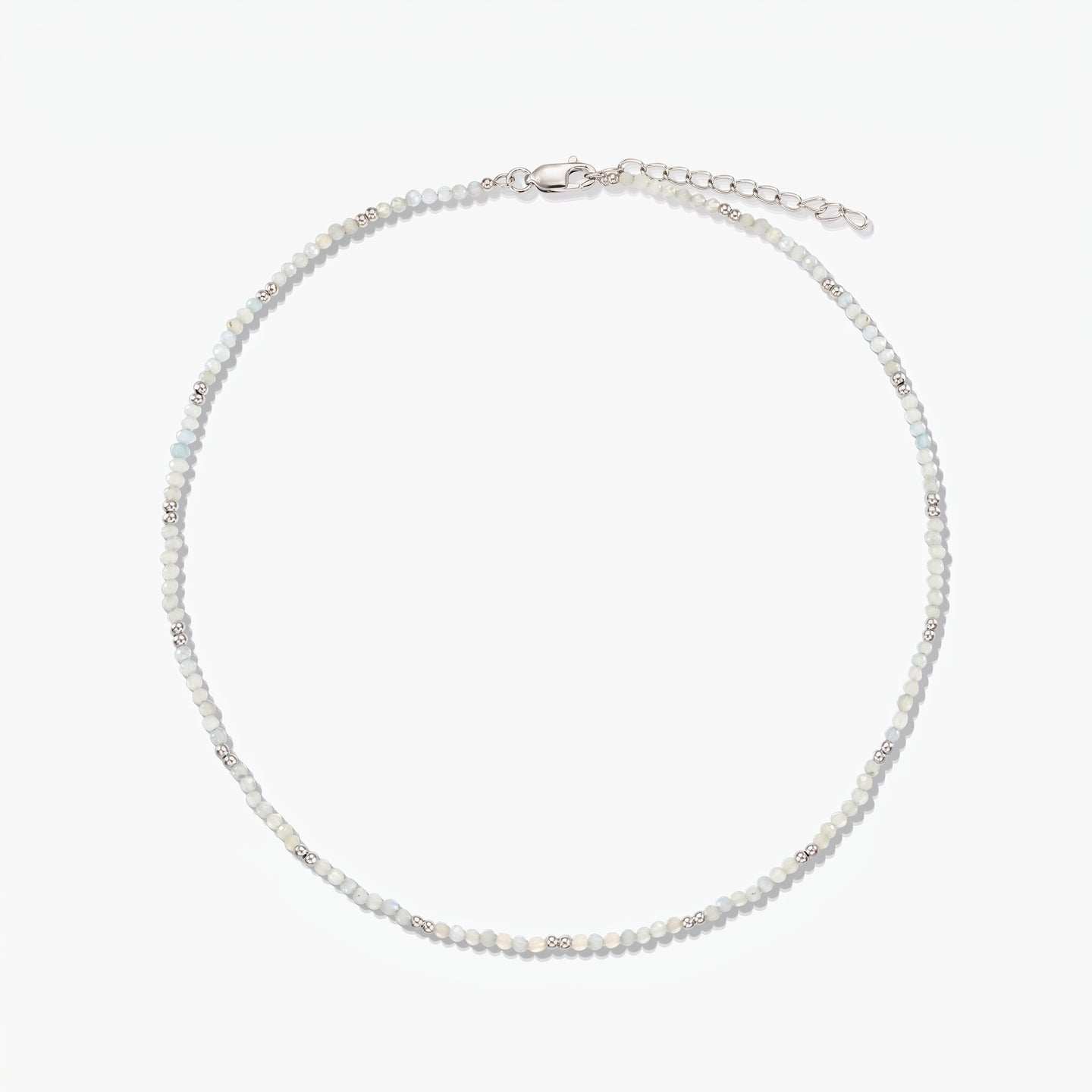 Collana in argento sterling delicata con piccole perline di pietra di luna e catena di prolunga regolabile, fotografata su sfondo bianco.