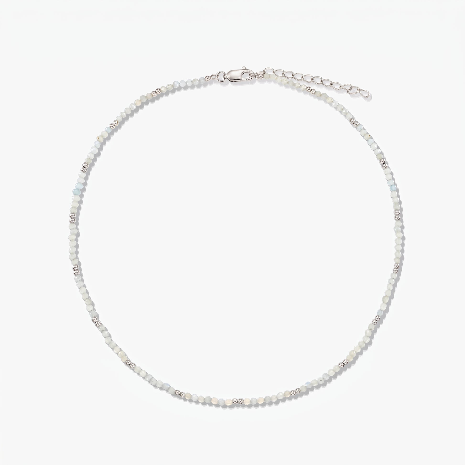 Collana in argento sterling delicata con piccole perline di pietra di luna e catena di prolunga regolabile, fotografata su sfondo bianco.