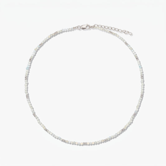 Collana in argento sterling delicata con piccole perline di pietra di luna e catena di prolunga regolabile, fotografata su sfondo bianco.