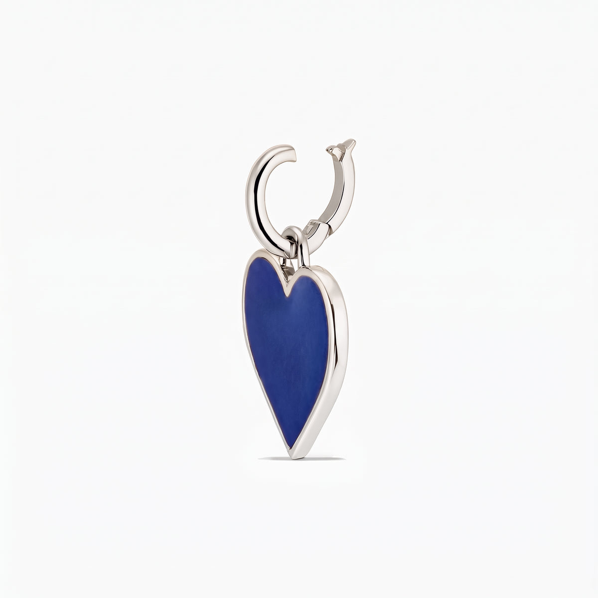 Primo piano di un pendente a forma di cuore in argento con un inserto blu profondo su sfondo bianco.