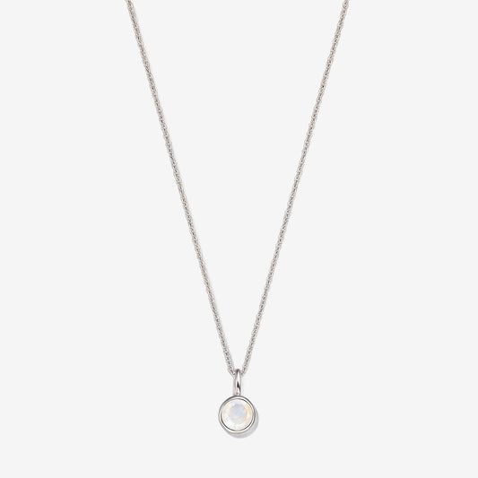 Collana in argento sterling con un piccolo pendente rotondo in pietra di luna incastonata a castone su una catena sottile, fotografata su sfondo bianco.