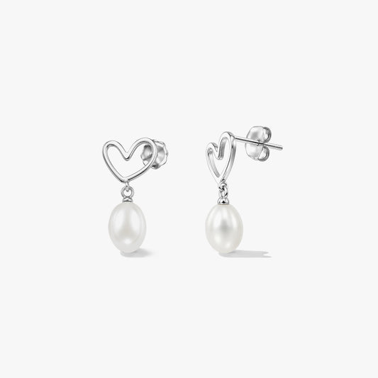 Orecchini a lobo a forma di cuore in argento sterling con perle bianche naturali pendenti su sfondo bianco.
