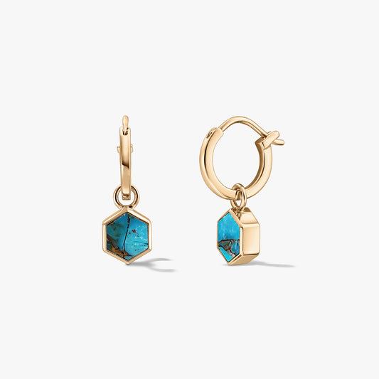 Coppia di piccoli orecchini a cerchio huggie in tono oro con ciondoli esagonali in pietra turchese blu-rame su sfondo bianco.