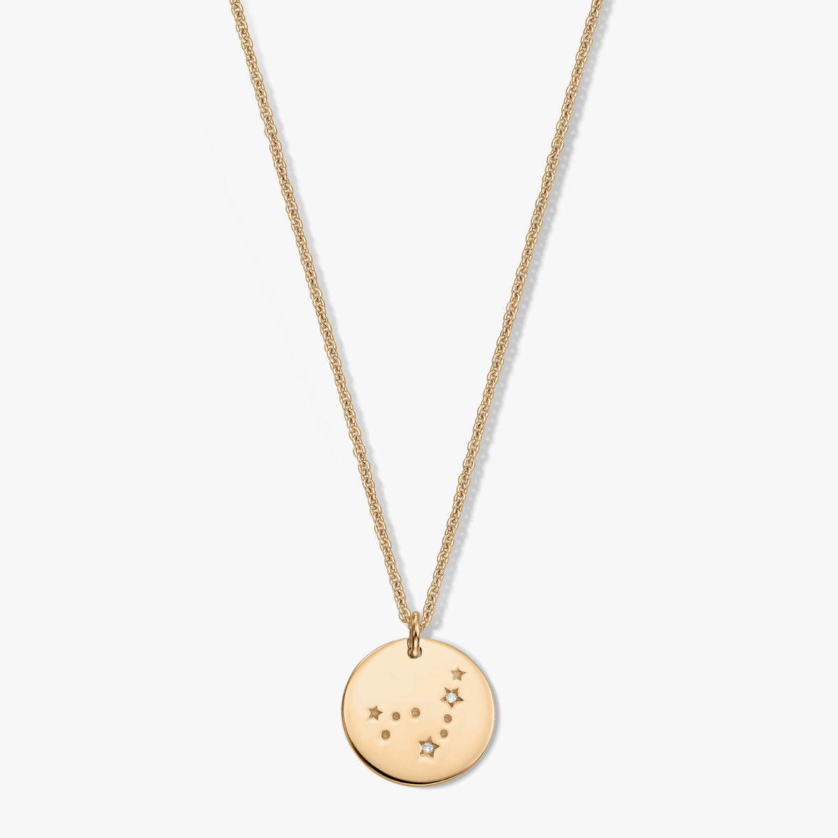 Collana con ciondolo rotondo del Capricorno in tono oro con piccoli accenti di zaffiro bianco su una catena delicata, isolata su sfondo bianco.