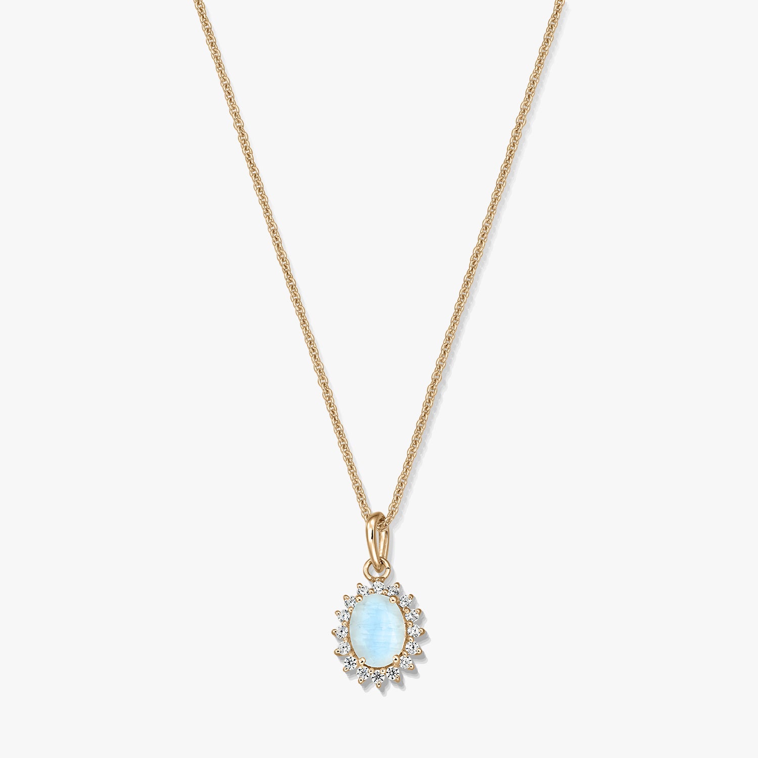 Collana in argento sterling placcato oro con un pendente ovale in pietra di luna azzurro chiaro, incorniciato da piccole pietre trasparenti, su sfondo bianco.