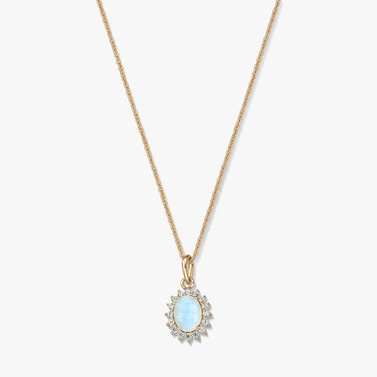 Collana in argento sterling placcato oro con un pendente ovale in pietra di luna azzurro chiaro, incorniciato da piccole pietre trasparenti, su sfondo bianco.
