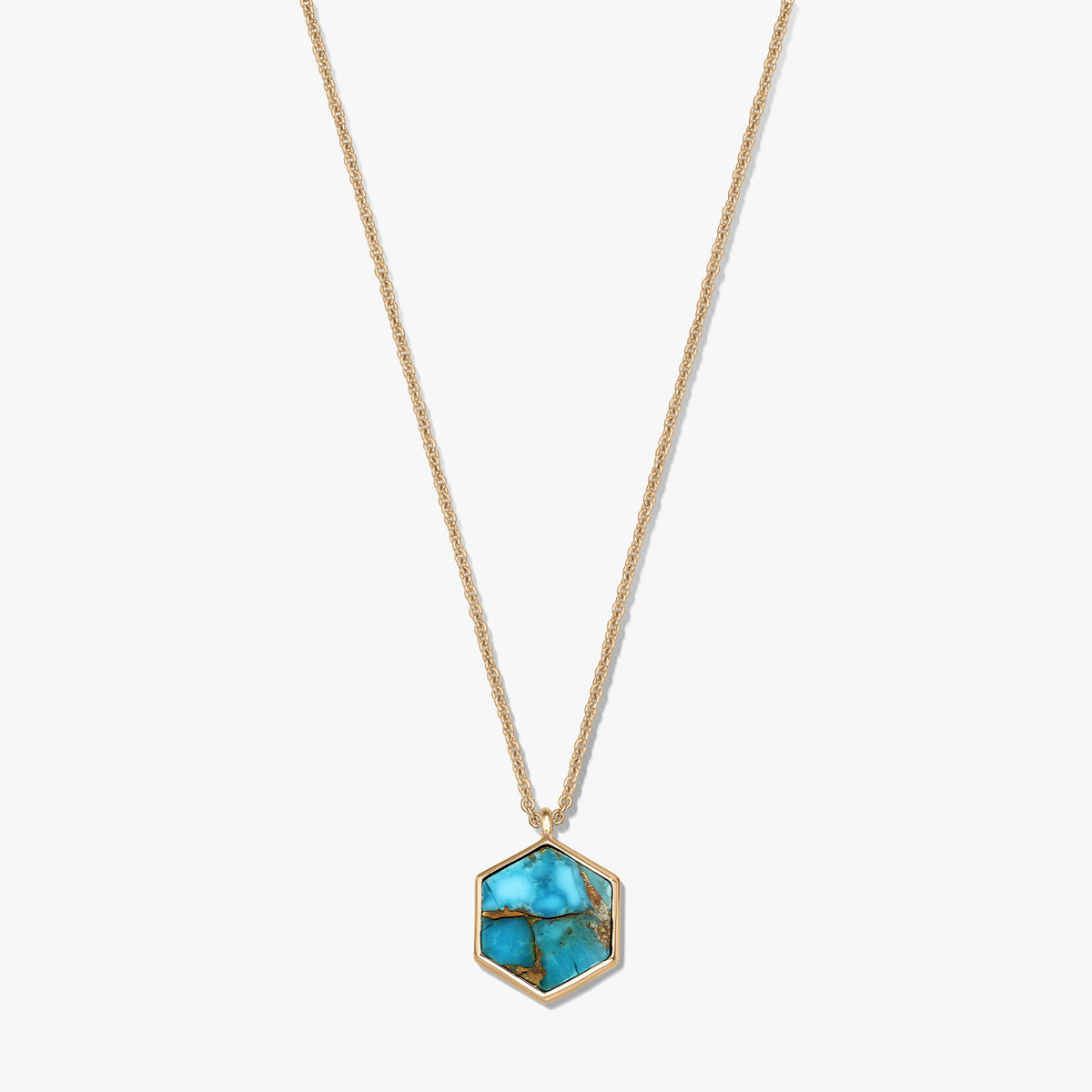 Collana in argento sterling placcato oro con pendente esagonale in rame color turchese, su sfondo bianco.
