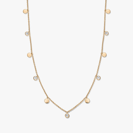 Collana a stazioni in argento sterling placcato oro con piccoli ciondoli a disco lucidi alternati e topazi bianchi incastonati a castone su una catena sottile, fotografata su sfondo bianco.