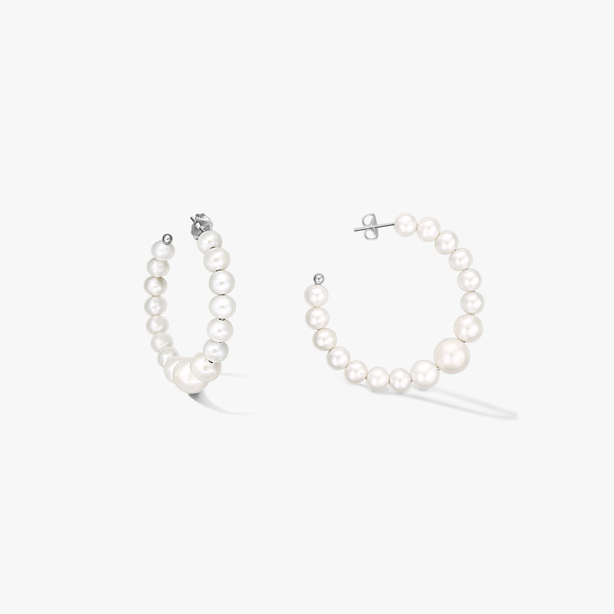 Coppia di orecchini a cerchio in argento sterling con perle naturali bianche a scalare, su sfondo bianco.