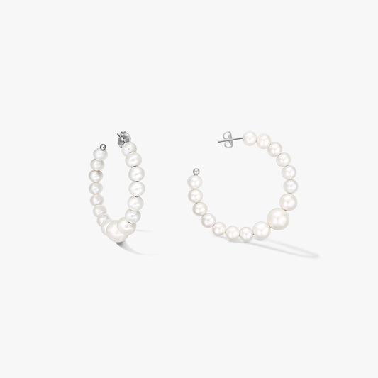 Coppia di orecchini a cerchio in argento sterling con perle naturali bianche a scalare, su sfondo bianco.