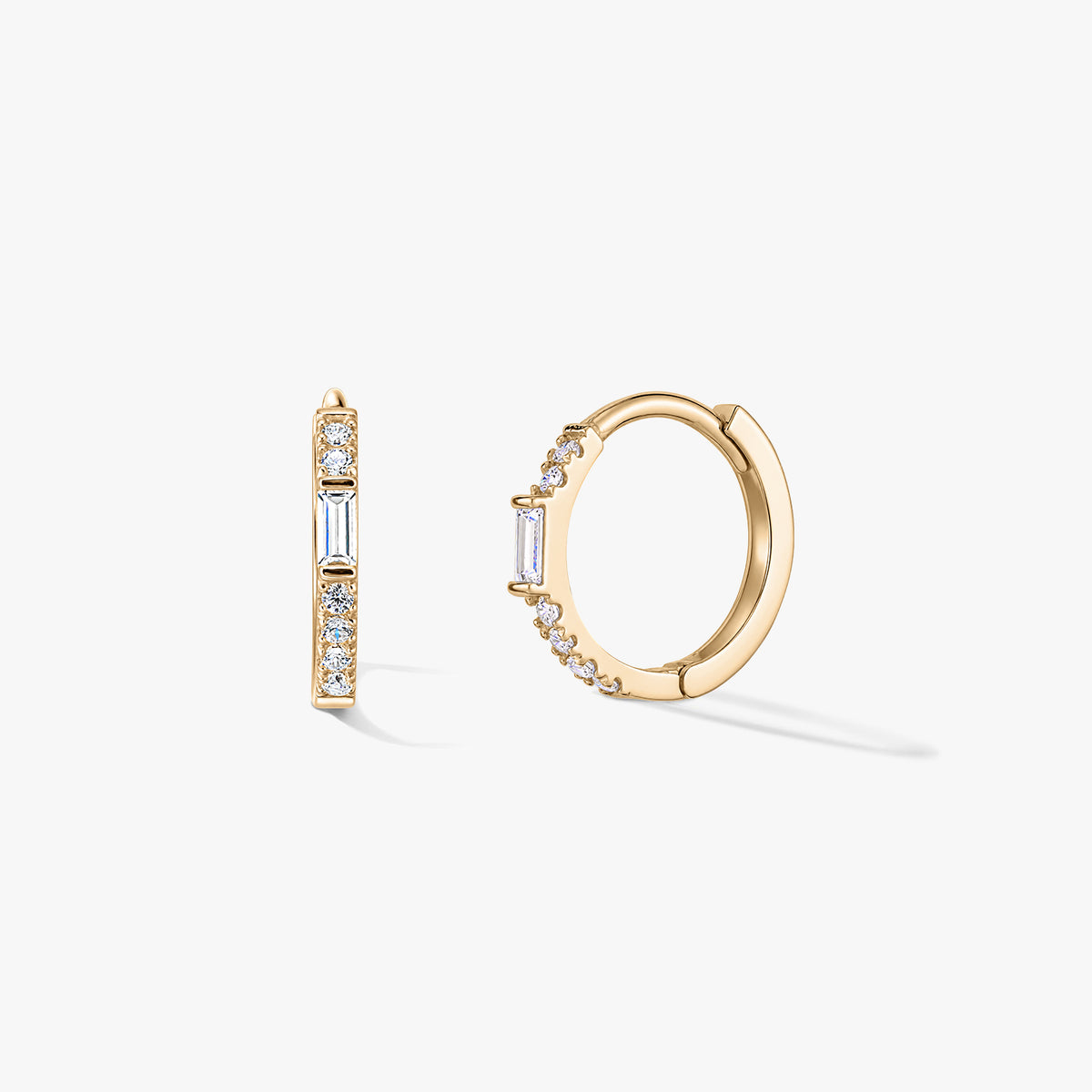 Coppia di orecchini a cerchio huggie in oro con pavé di zirconi chiari e un accento verticale baguette, mostrati su sfondo bianco.