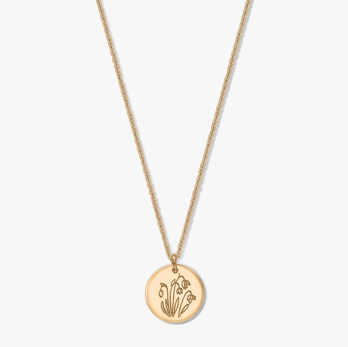 Collana in argento sterling placcato in oro con ciondolo a disco rotondo inciso con il fiore di nascita di gennaio, il bucaneve, su sfondo bianco.