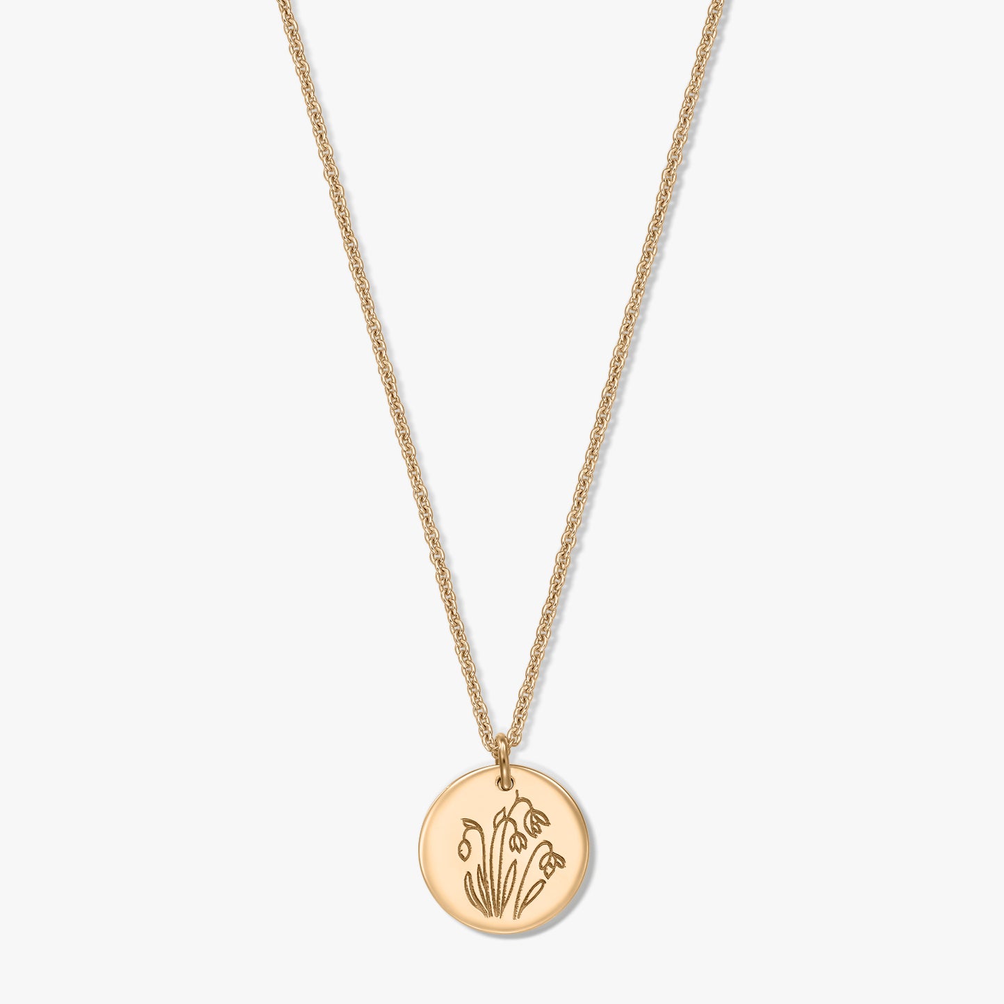 Collana in argento sterling placcato in oro con ciondolo a disco rotondo inciso con il fiore di nascita di gennaio, il bucaneve, su sfondo bianco.