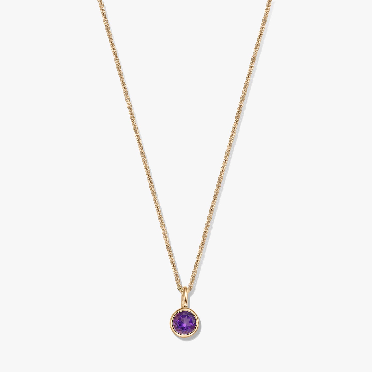 Collana in argento sterling placcato oro con un piccolo pendente rotondo con ametista come pietra di nascita su sfondo bianco.