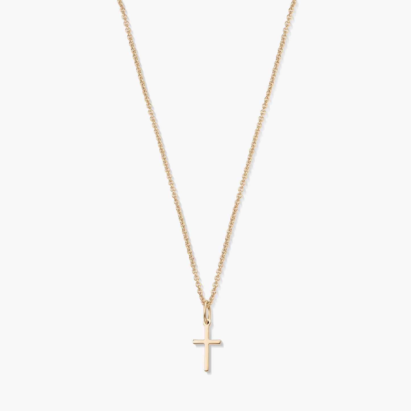 Collana minimalista in oro giallo 14K con un piccolo pendente a forma di croce su una catena fine, isolata su sfondo bianco.
