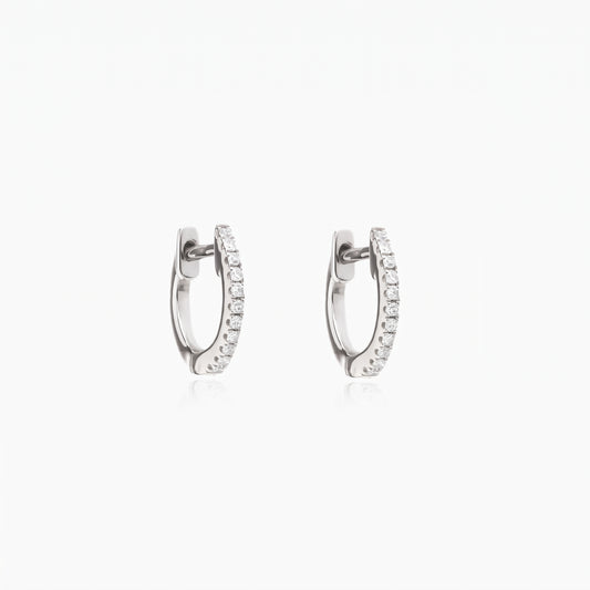 Coppia di orecchini a cerchio huggie Sadie in argento con zirconi trasparenti a pavé, su sfondo bianco.