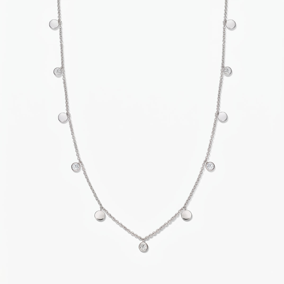 Collana a stazioni in argento sterling Noora con dischetti lucidi alternati e topazi bianchi incastonati a castone, su sfondo bianco.