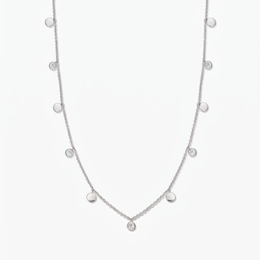 Collana a stazioni in argento sterling Noora con dischetti lucidi alternati e topazi bianchi incastonati a castone, su sfondo bianco.