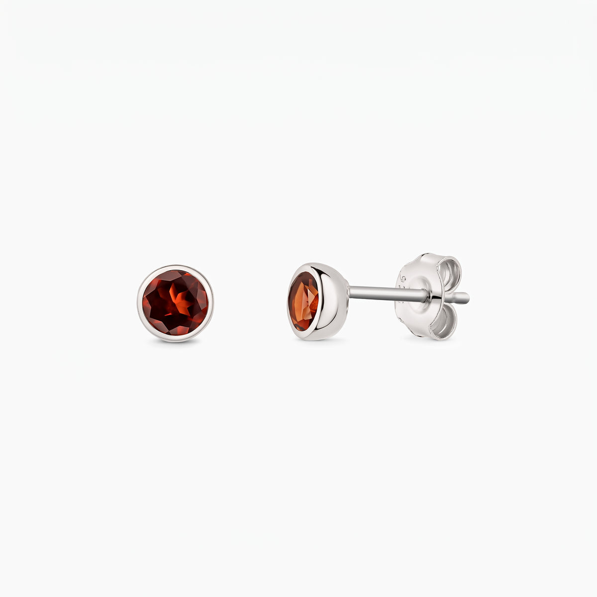 Coppia di orecchini a perno in argento sterling con pietre di granato rotonde, mostrati frontalmente e di profilo su sfondo bianco, con chiusure a farfalla visibili.