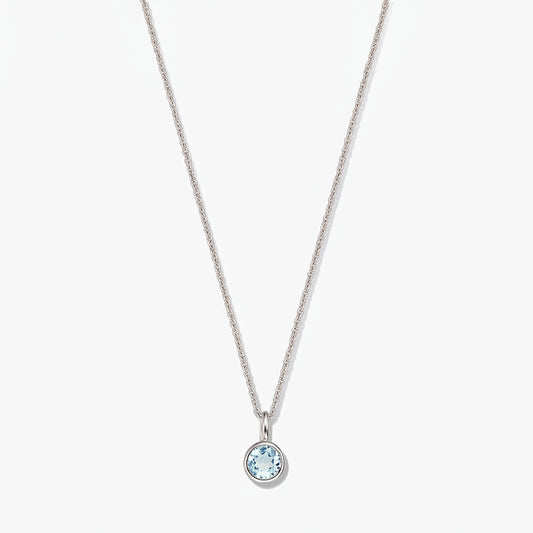 Elegante collana in argento sterling con pietra di nascita e piccolo ciondolo rotondo in topazio blu con montatura a castone, su sfondo bianco.