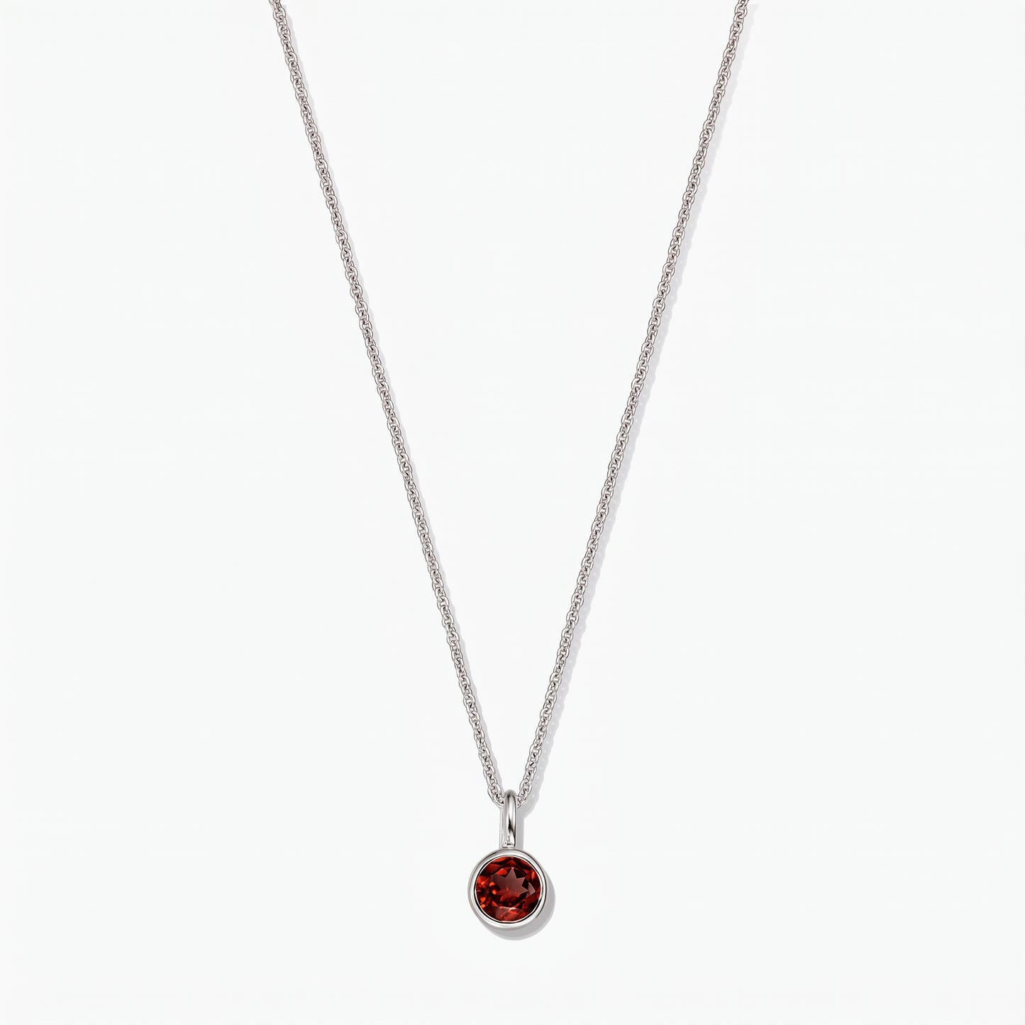 Collana in argento sterling con pietra di nascita, ciondolo in granato rotondo con montatura a castone, su sfondo bianco.