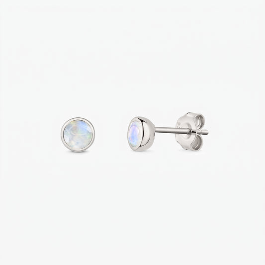 Coppia di orecchini a lobo in argento sterling 925 con pietre di luna rotonde iridescenti incastonate a castone, su sfondo bianco; mostrati frontalmente e di lato con chiusura a farfalla.