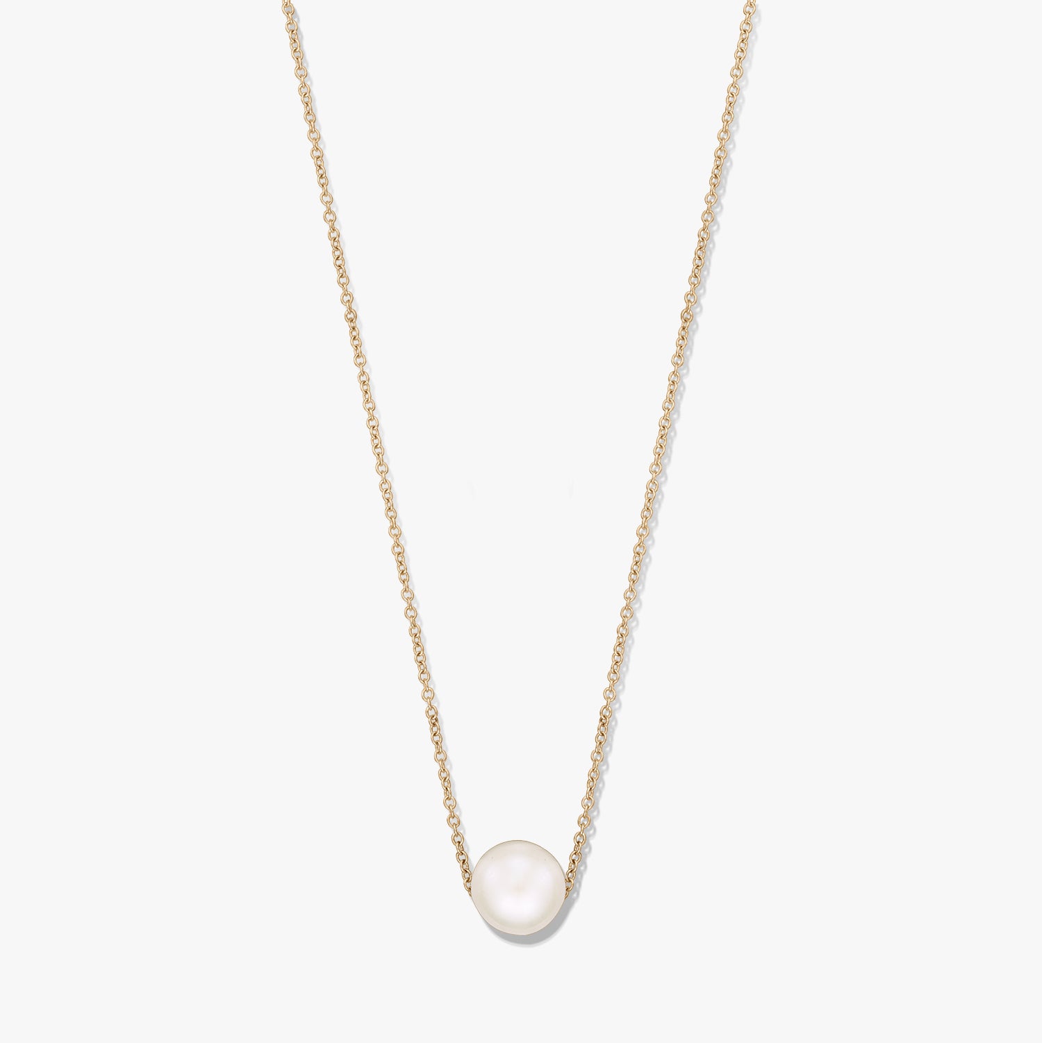 Collana a catena delicata con una singola perla naturale bianca al centro su una catena color oro, isolata su sfondo bianco.
