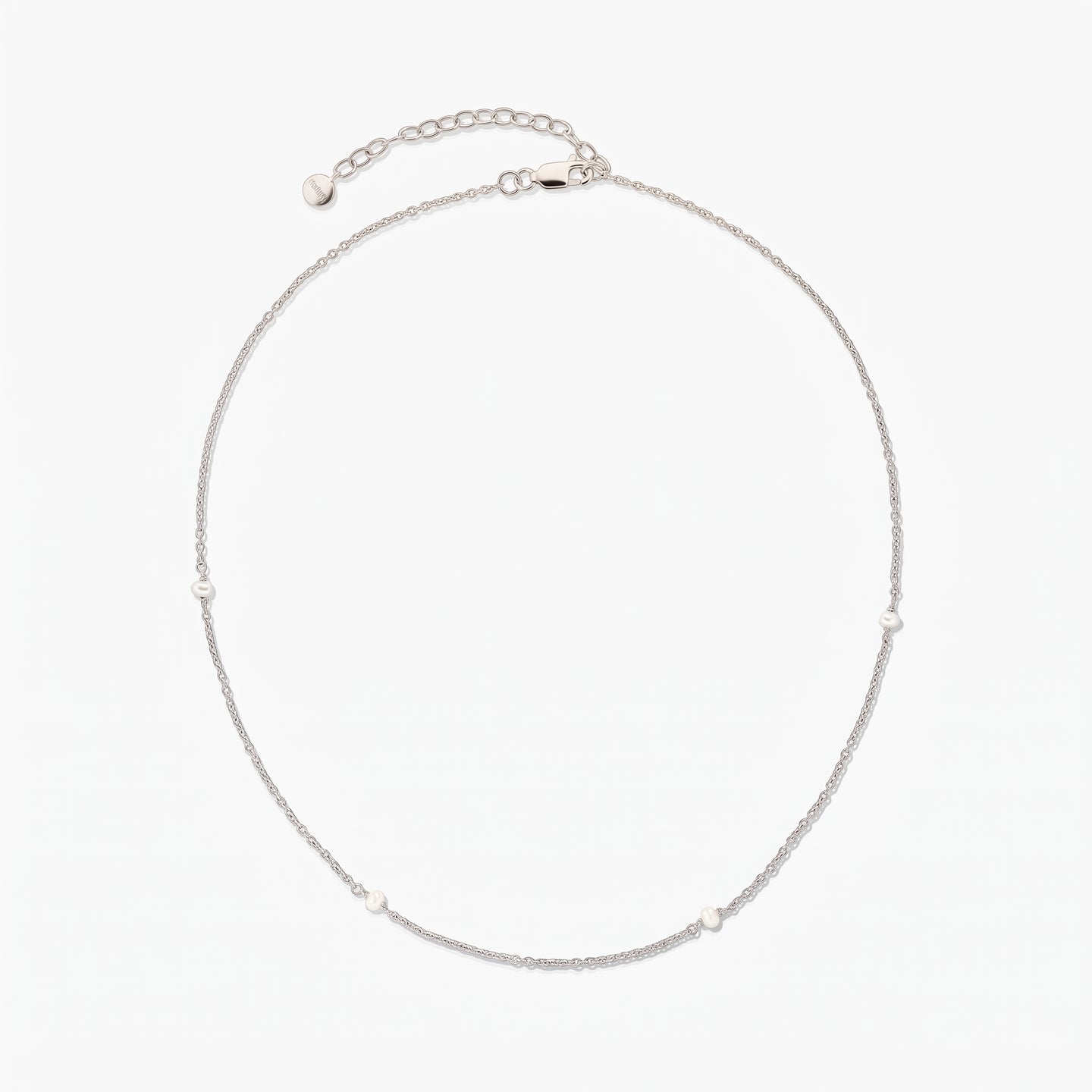 Collana a catena in argento, elegante e delicata, con piccole perle bianche a intervalli; disposta a cerchio su sfondo bianco, con prolunga regolabile e chiusura a moschettone.