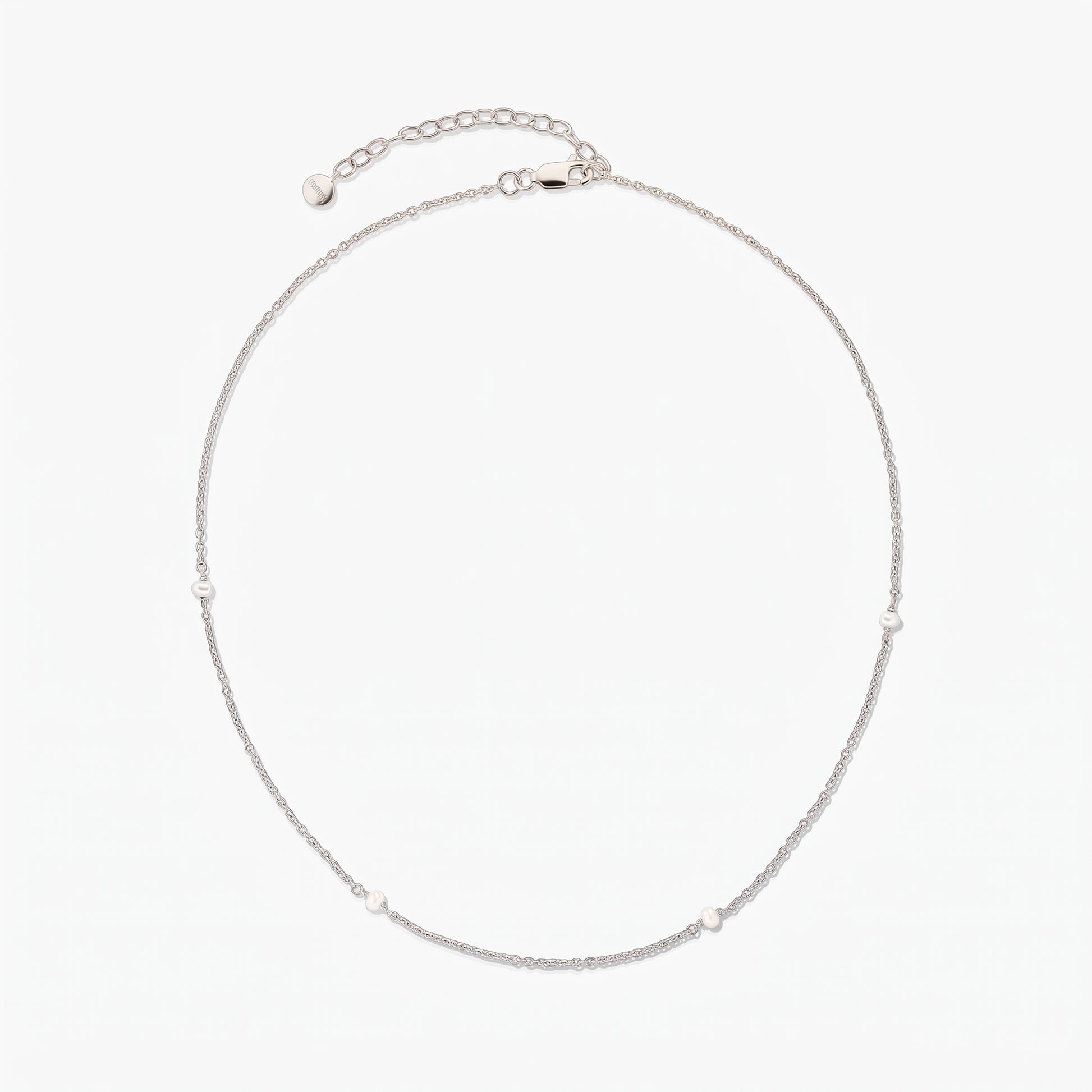 Collana a catena in argento, elegante e delicata, con piccole perle bianche a intervalli; disposta a cerchio su sfondo bianco, con prolunga regolabile e chiusura a moschettone.