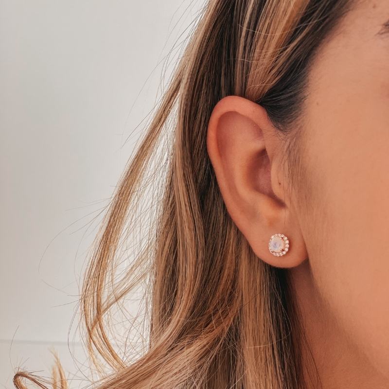 Primo piano di un orecchio che indossa un orecchino in argento Keira Rose con pietra di luna su sfondo chiaro.