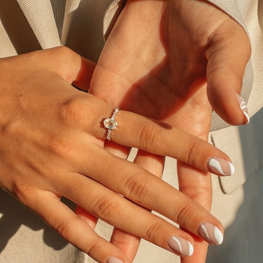 Mani che mostrano un Anello Selah in Argento con pietra di luna su uno sfondo delicato.