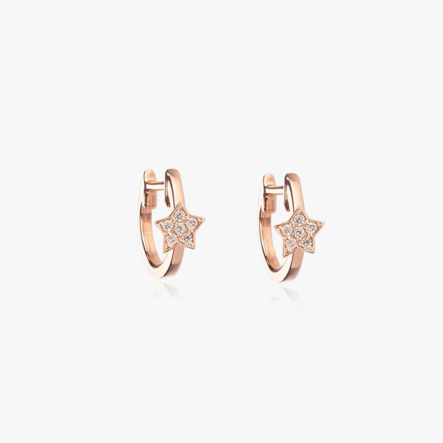 Paio di orecchini circolari in oro rosa con zirconi a forma di stella su sfondo bianco.