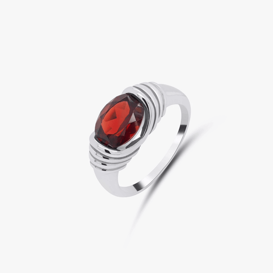Anello in argento con gemma centrale granato rosso su sfondo bianco.