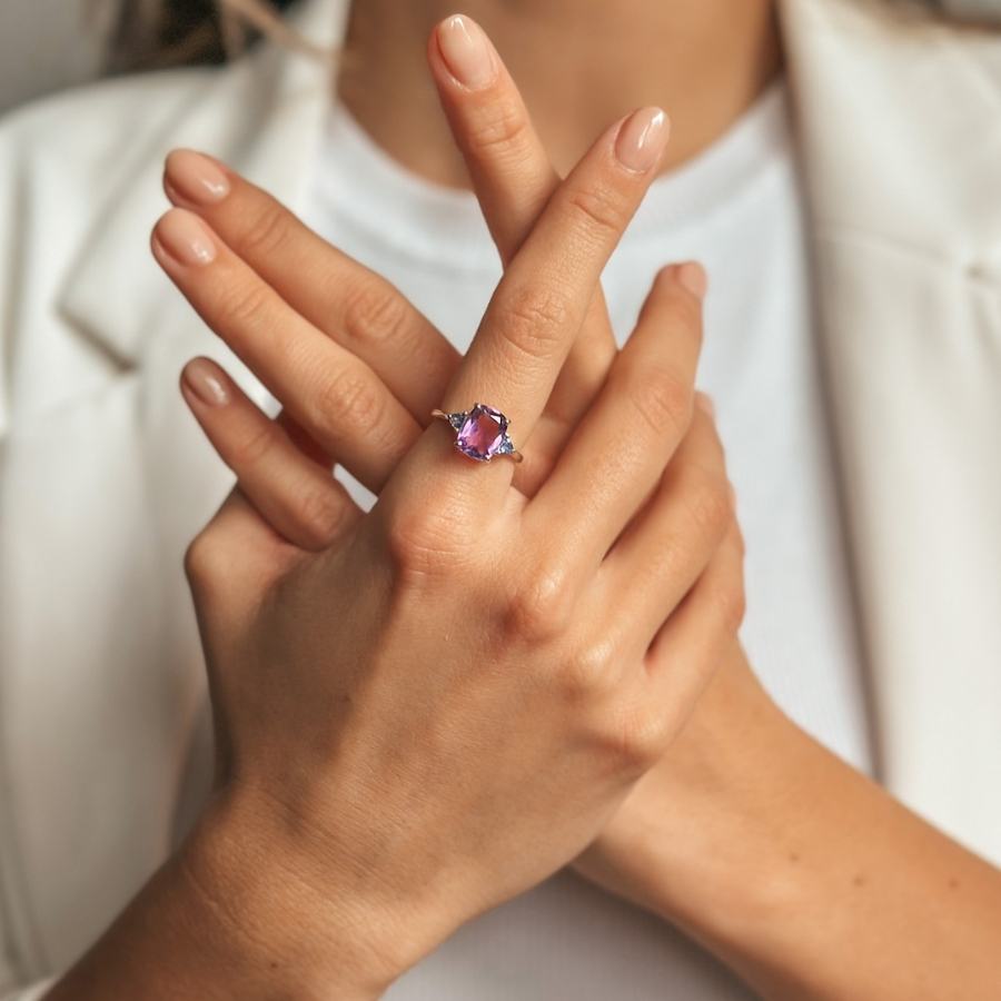 Mani incrociate che mostrano un anello d'argento con pietre di ametista e tanzanite.