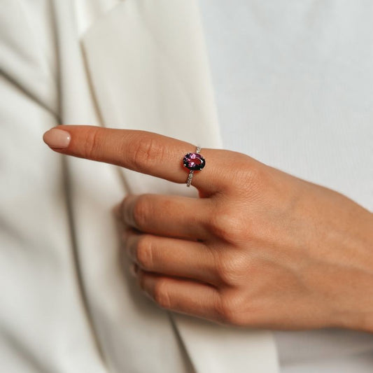 Close-up di una mano che indossa un anello d'argento con ametista e zirconi.