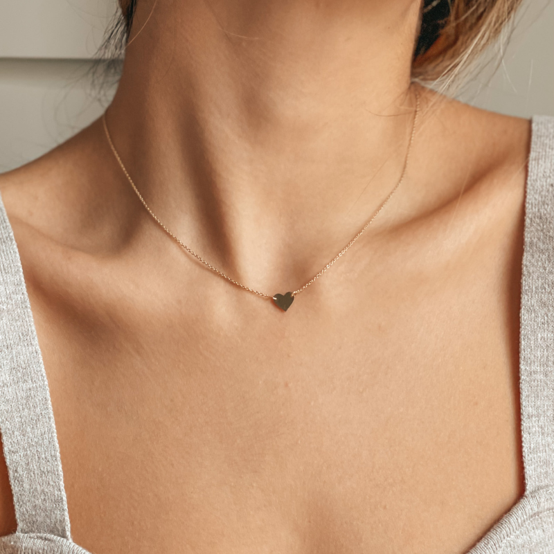 Collo di donna con un delicato collier a cuore in oro 14K.
