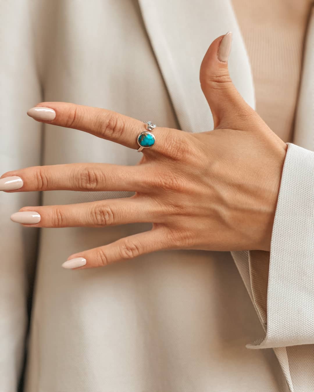Primo piano di una mano che indossa un anello d'argento con topazio azzurro e turchese.